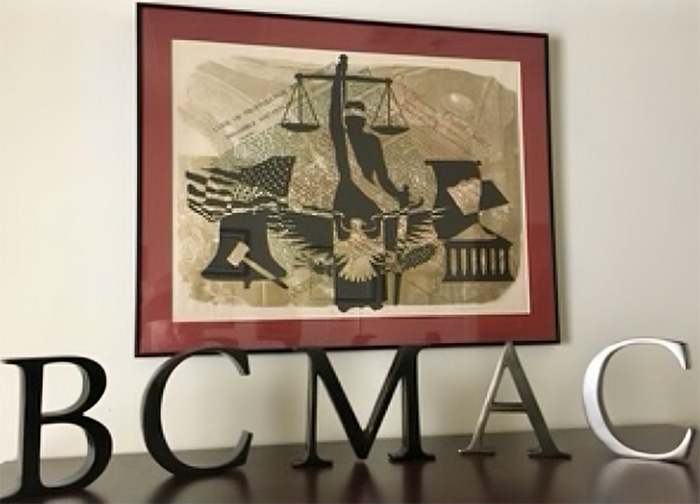 Office Table With The Letters "BCMAC" Standing Before A Framed Piece Of Art
